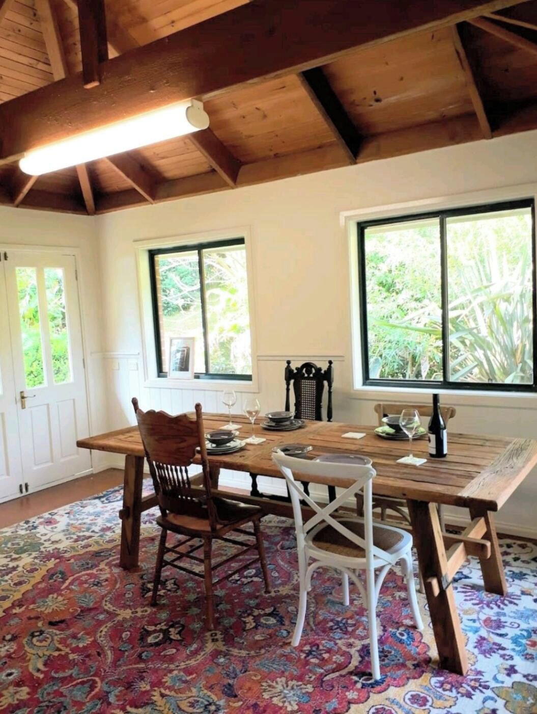 Un comedor con mesa de madera, sillas y alfombra estampada.