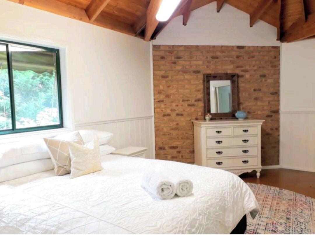 A luxury bed with quality linens and high wooden ceilings.