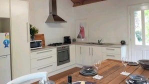 A spacious kitchen with a large rustic table, essential appliances, and overlooks cottage gardens. - Sandys Pottery Cottage- pet friendly, wineries, (Healesville)