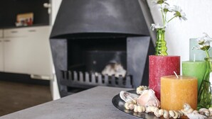 Een moderne keuken met een zwarte open haard, een dienblad met schelpen en drie kaarsen in rood, groen en geel.
