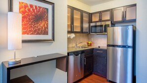 Una cocina moderna con electrodomésticos de acero inoxidable, armarios oscuros y una obra de arte floral enmarcada en la pared.
