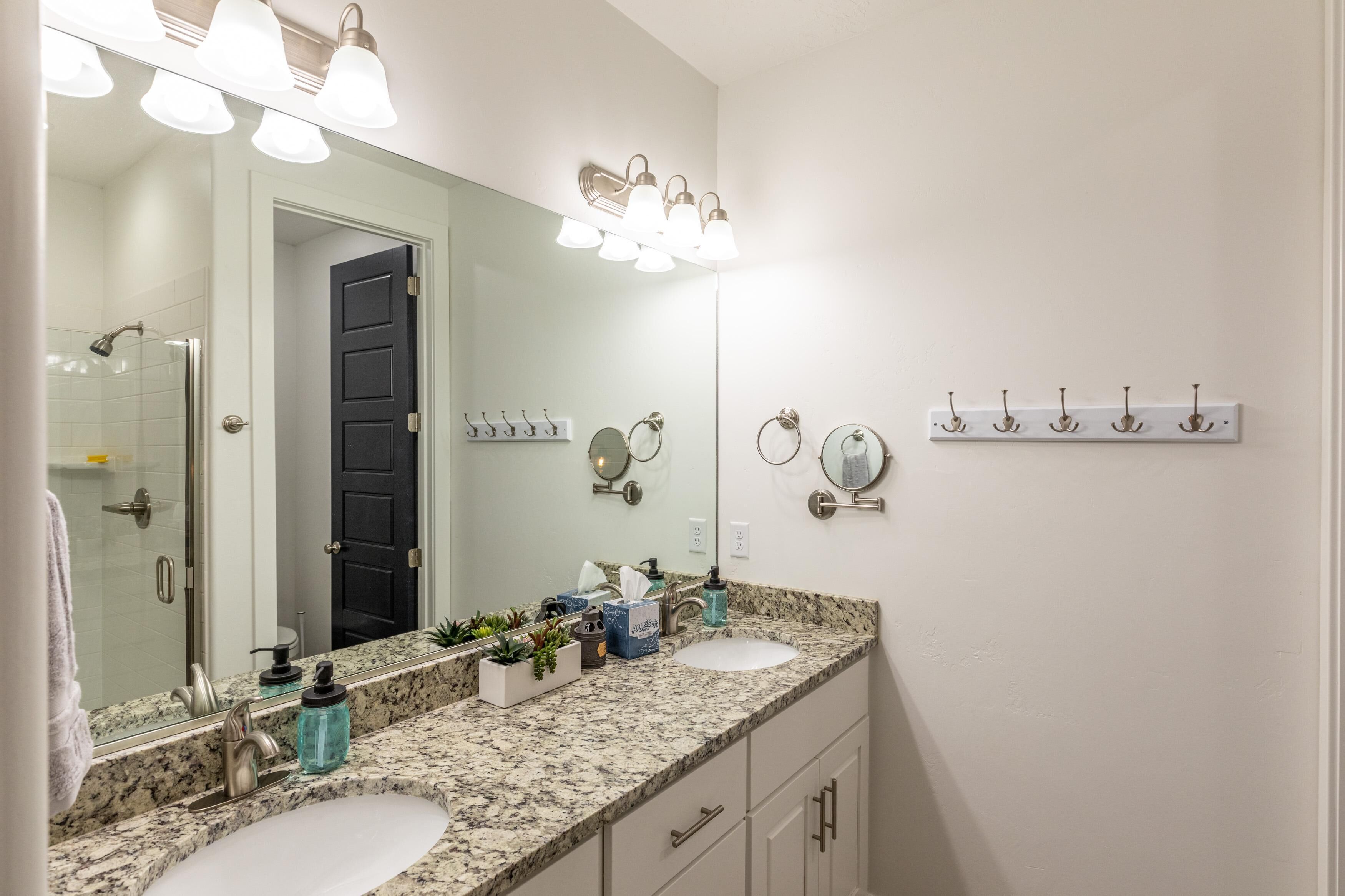 A bathroom with two sinks, a large mirror, and a shower.