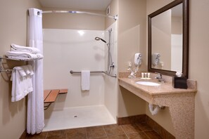 Un bany amb dutxa, un lavabo, un mirall i tovalloles.