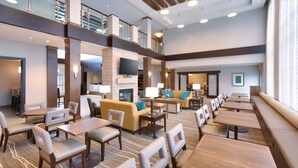 A spacious hotel lobby with multiple seating areas, including sofas and tables, and a high ceiling with exposed beams.