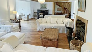 Un salon spacieux avec un haut plafond, une cheminée et un escalier menant à l’étage supérieur.