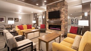 A modern lounge area with comfortable seating, a fireplace, and a flat-screen TV mounted on a stone wall.