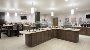 A modern kitchen with a central island, bar stools, and a seating area.