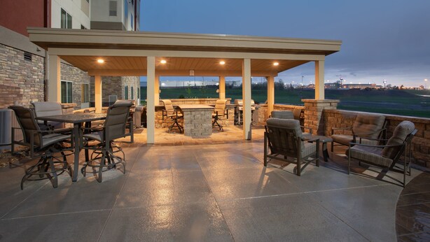 An outdoor patio with a covered seating area, stone pillars, and a view of the landscape.
