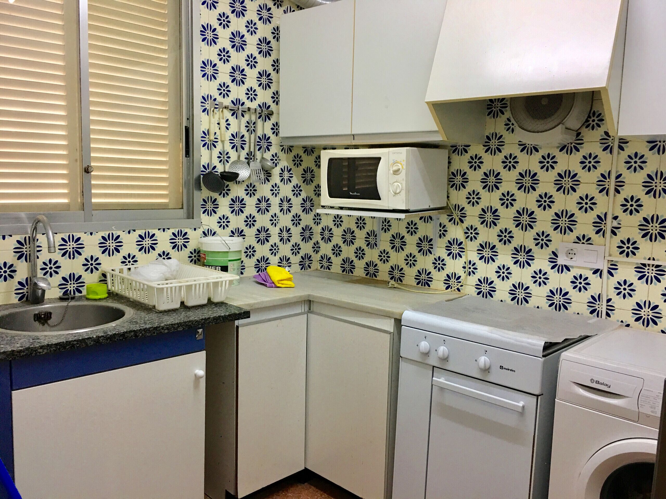 Ett kompakt kök med diskho, mikrovågsugn och tvättmaskin.