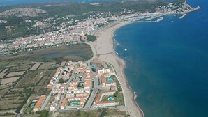 An aerial view of a coastal resort with a beachfront, a marina, and a residential area with buildings and roads. - ROCAMAURA II 1-5 (Estartit)
