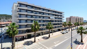 A multi-story hotel with balconies, palm trees, and a clear sky. - ROCAMAURA II 1-5 (Estartit)