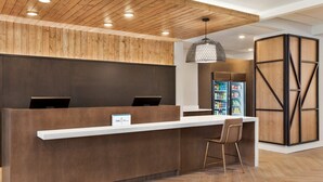 Una recepción con techo de madera, una lámpara colgante y un refrigerador lleno de bebidas.
