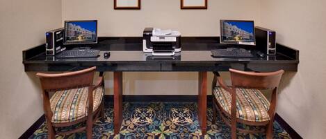 A hotel reception desk with two computers, a printer, and two chairs.