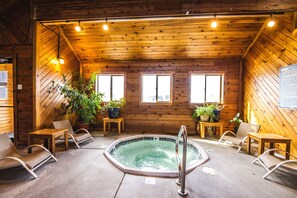 Una cabaña de madera con jacuzzi, asientos y plantas en macetas.
