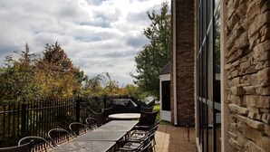 An outdoor patio with a long table and chairs, a barbecue grill, and a stone wall. - Free Breakfast. Gym. Near Mercy Hospital Northwest Arkansas! (Rogers)