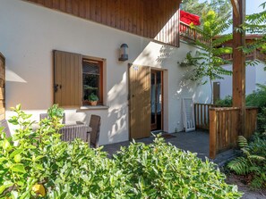 Un bâtiment doté d’un balcon en bois, d’une porte avec un numéro et d’une fenêtre ornée d’une plante.