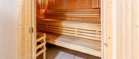 Una sauna con panche in legno e una porta di legno.