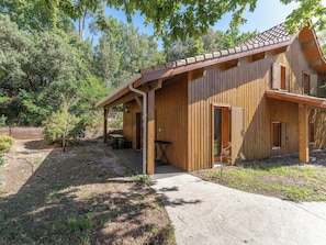 Une cabane en bois dotée d’un porche abrité, d’une petite table et d’un banc.