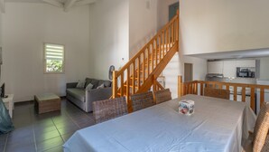 A spacious living area with a large bed, a wooden staircase, a sofa, and a kitchen area.