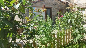 A stone house with a wooden fence, a satellite dish, and a wooden bench. - 5routes apartments connecting with nature (Vimianzo)