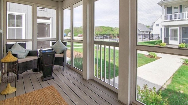 A covered porch with wicker furniture and a view of a residential street. - Captain`s Quarters - 179 Leeward Way, Cottage #6 (Ottawa)