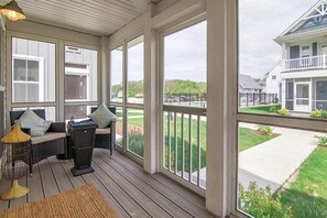 A covered porch with wicker furniture and a view of a residential street. - Captain`s Quarters - 179 Leeward Way, Cottage #6 (Ottawa)