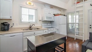 A compact kitchen with white cabinets, a microwave, stove, and a dishwasher. - Captain`s Quarters - 179 Leeward Way, Cottage #6 (Ottawa)