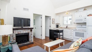 A living room with a stone fireplace, a television, and a sofa. - Captain`s Quarters - 179 Leeward Way, Cottage #6 (Ottawa)