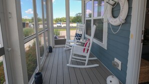 En inglasad veranda med en gungstol och en vit räddningsboj.