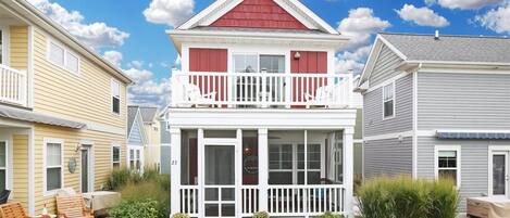 A two-story house with a balcony, a front porch, and a small garden area with plants and outdoor furniture.