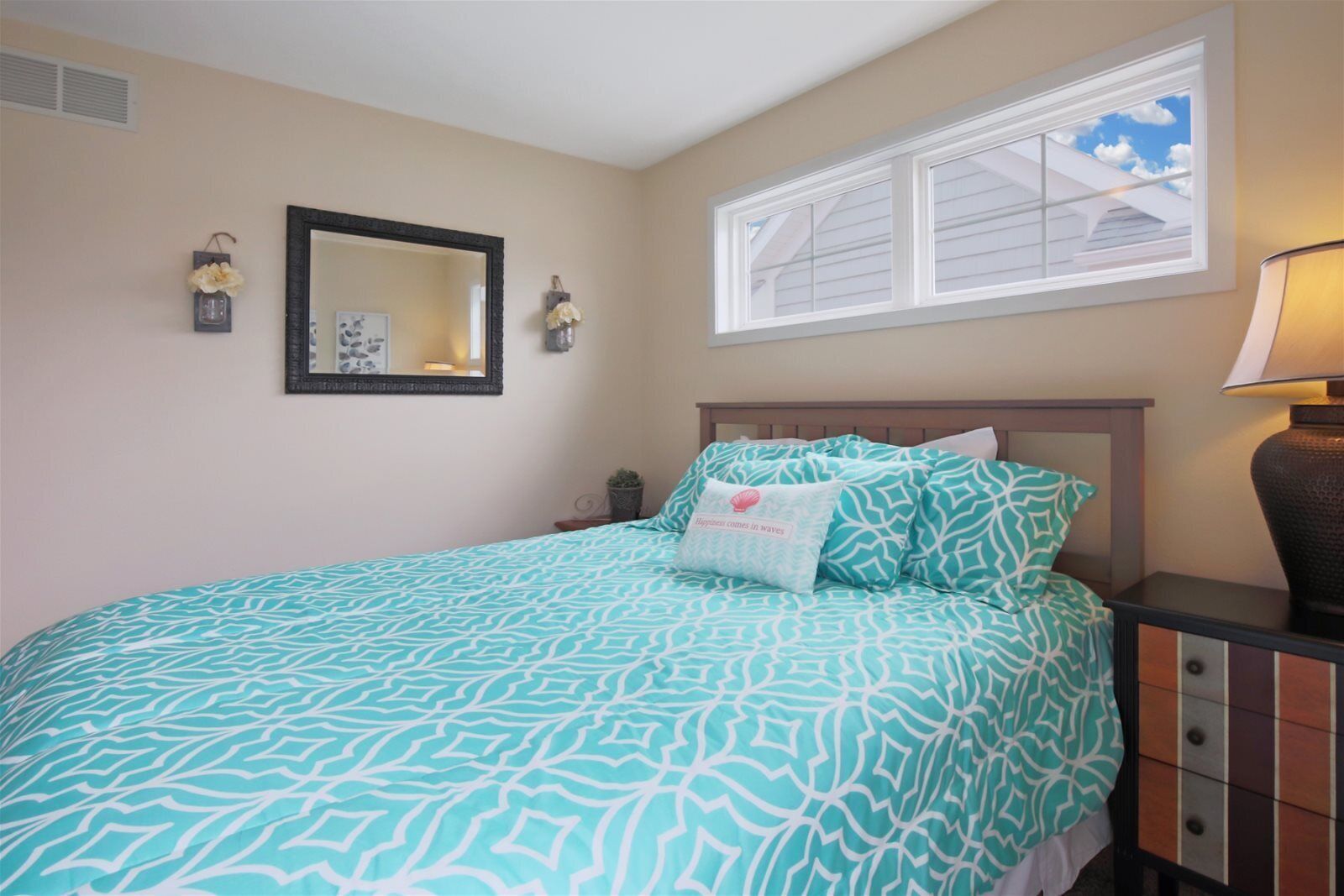A bedroom with a bed, a nightstand, a lamp, a window with a view, and wall-mounted lights.