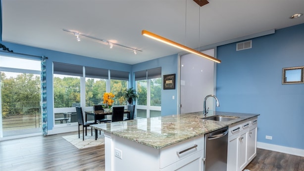A modern kitchen with a large island, built-in dishwasher, and a dining area with a table and chairs. - Serenity 41W (Ottawa)