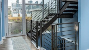 A modern interior with a staircase, large windows, and a view of residential buildings. - Serenity 41W (Ottawa)