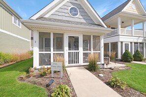 A two-story house with a covered porch, a sign reading "Our Happy Place #2", and a well-maintained lawn.