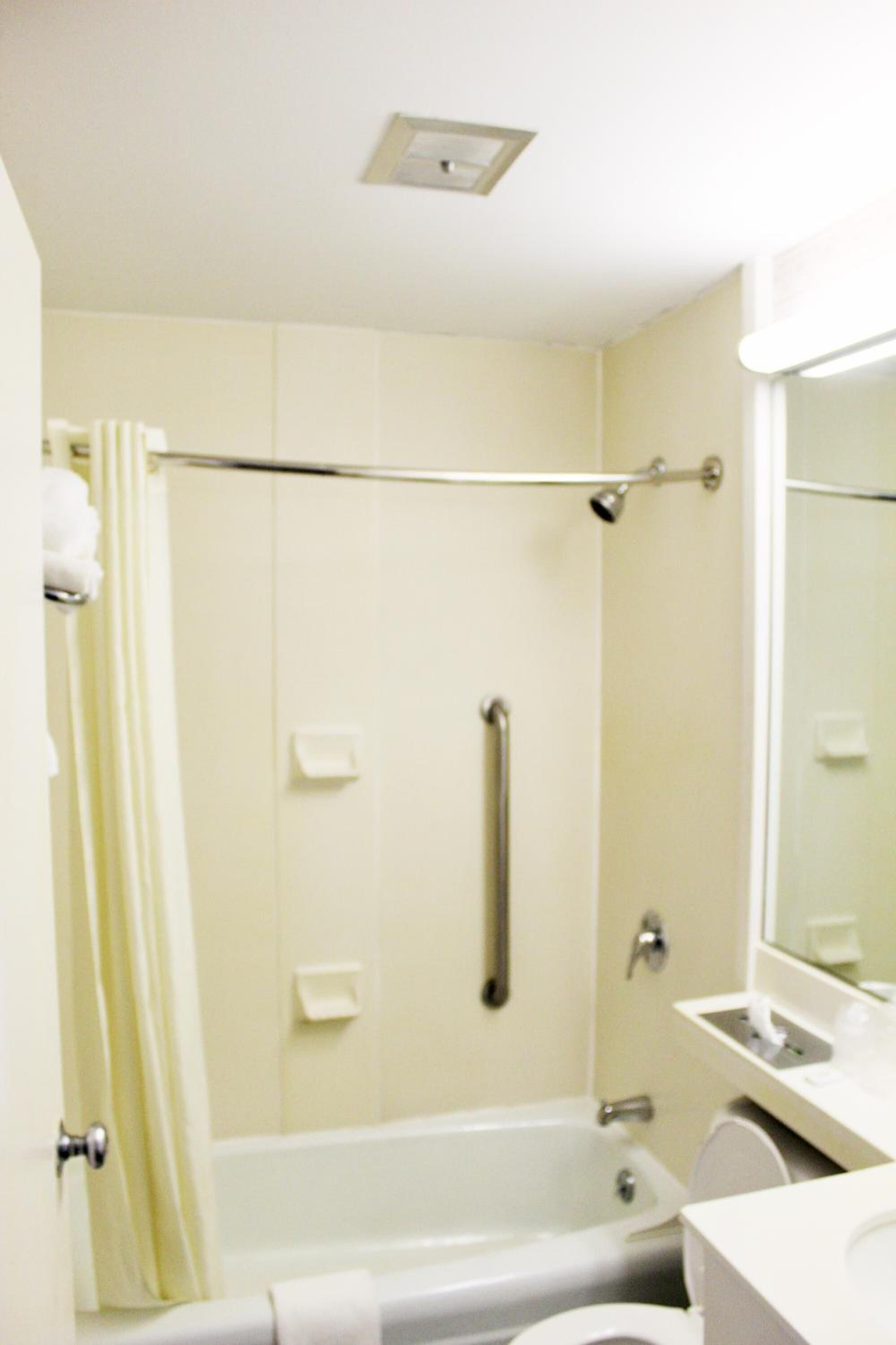 A bathroom with a bathtub, a toilet, a sink, and a mirror.