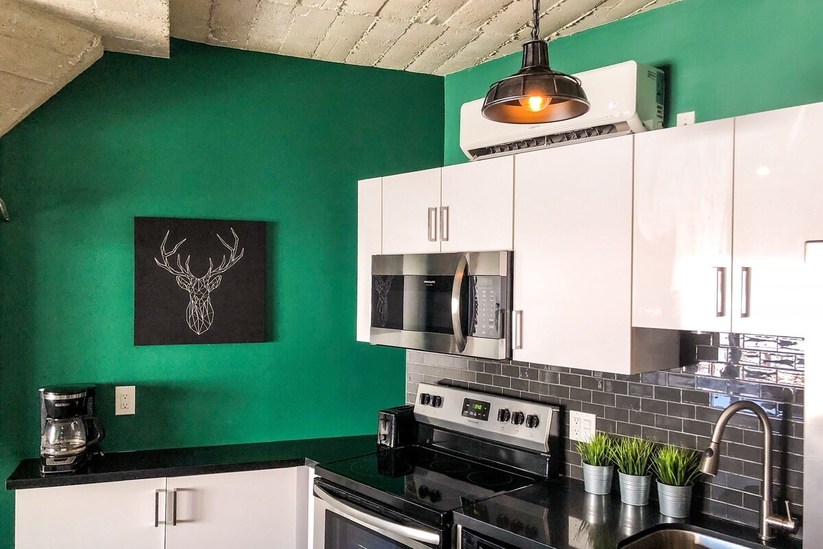 A kitchen with white cabinets, a black countertop, a microwave, an oven, and a coffee maker.
