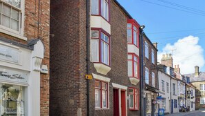 A row of traditional brick buildings with red-framed windows and a clear blue sky.