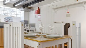 A dining area with a wooden table set for four, white chairs, and a white cabinet with a tiled backsplash.