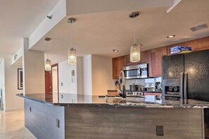 A modern kitchen with a large island, stainless steel appliances, and pendant lighting.