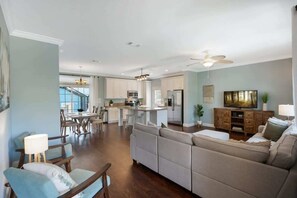 A spacious living area with a large sofa, a dining table, and a kitchen in the background.
