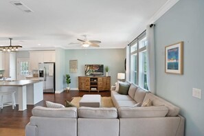 A spacious living area with a sofa, a dining table, and a kitchen in the background.
