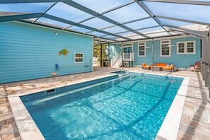 Ein Swimmingpool mit überdachter Terrasse, einer Treppe zu einem Deck und Gartenmöbeln.