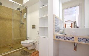 Ein modernes Badezimmer mit einer Duschkabine, einer Toilette und einem Waschbecken mit Spiegel darüber.