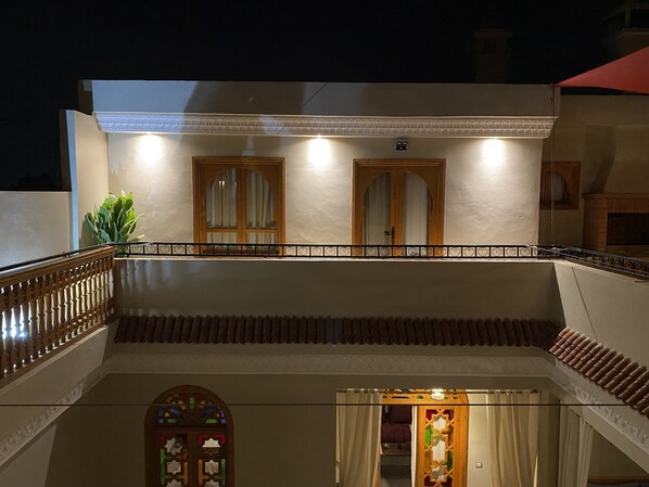 A two-story building with a balcony, a wooden door, and a window with a decorative design. - Riad Shajara (Marrakech)
