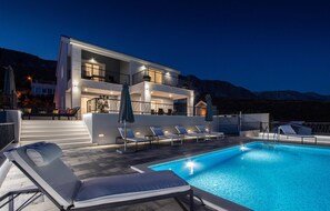 A modern two-story building with a swimming pool, outdoor seating, and a mountain backdrop. - Amazing home in Kucine (Kucine)