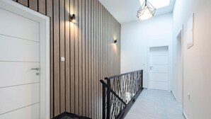 A modern hallway with a wooden accent wall, a black railing, and a skylight.