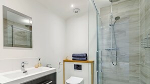 A modern bathroom with a glass-enclosed shower, a white sink with a mirror above, and a wooden vanity with drawers. - The Old Dairy At Wooton - UKC4355 (East Chiltington)