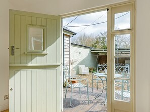 A room with a door leading to an outdoor patio area with metal chairs and a table. - The Old Dairy At Wooton - UKC4355 (East Chiltington)