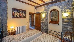 Un dormitorio con una cama, un cuadro, una pared de piedra y una puerta de madera.