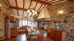 Una cocina rústica con vigas a la vista, una pared de piedra y una mesa de madera.